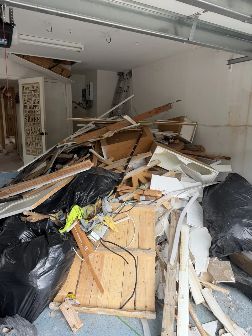Garage floor stacked with lumber, debris and bagged junk before a Rapid Haul cleanout