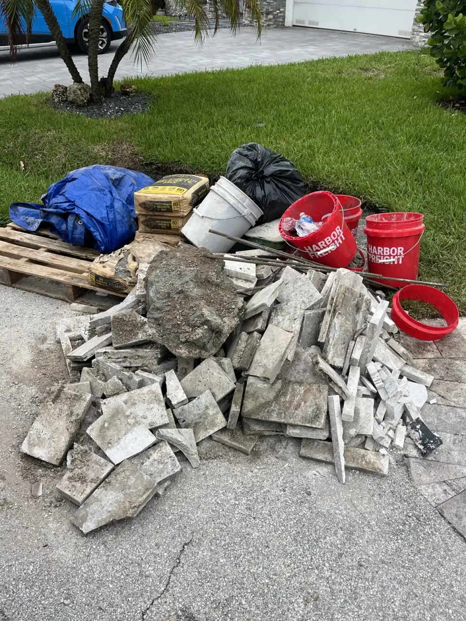Broken concrete pieces piled beside a cleared patio area during a concrete removal job