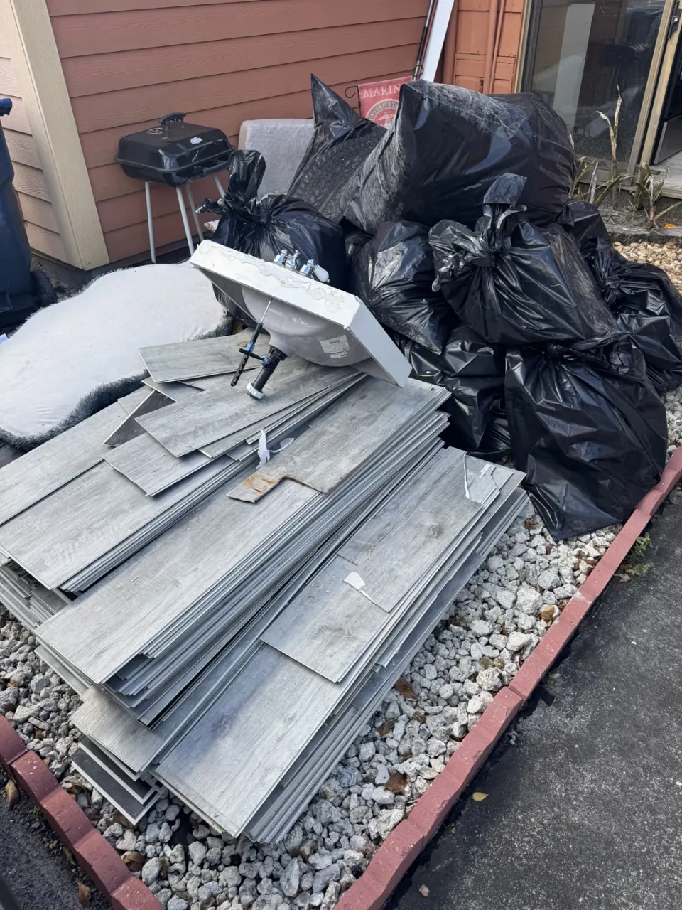 Pile of renovation debris, drywall and lumber beside a house, ready to be loaded