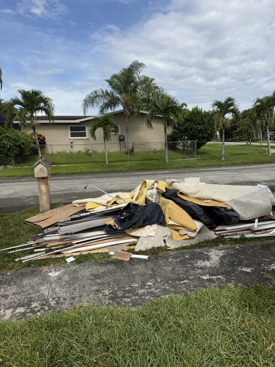 Curbside pile of old carpet, drywall and boards waiting for junk removal
