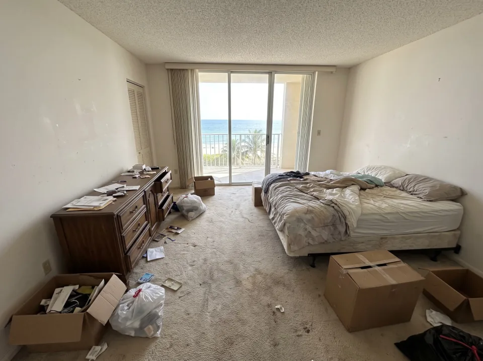 Illustration: a dated condo unit interior in a South Florida high-rise: carpet, popcorn ceiling, mirrored closet doors, old built-in bar cabinet, ocean view through the balcony glass.